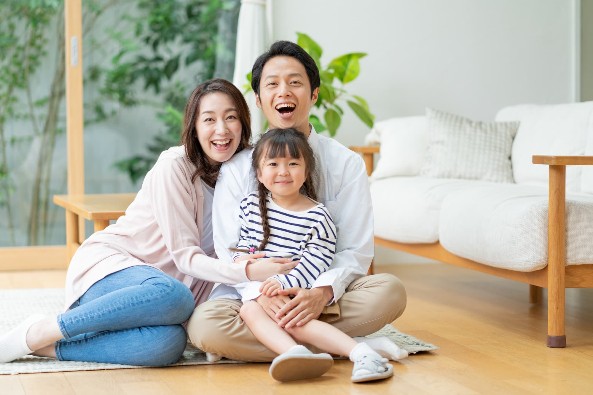 笑顔の子どもを膝に乗せるパパと横で寄り添うママ