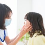 受け口をチェックする歯科衛生士と子ども