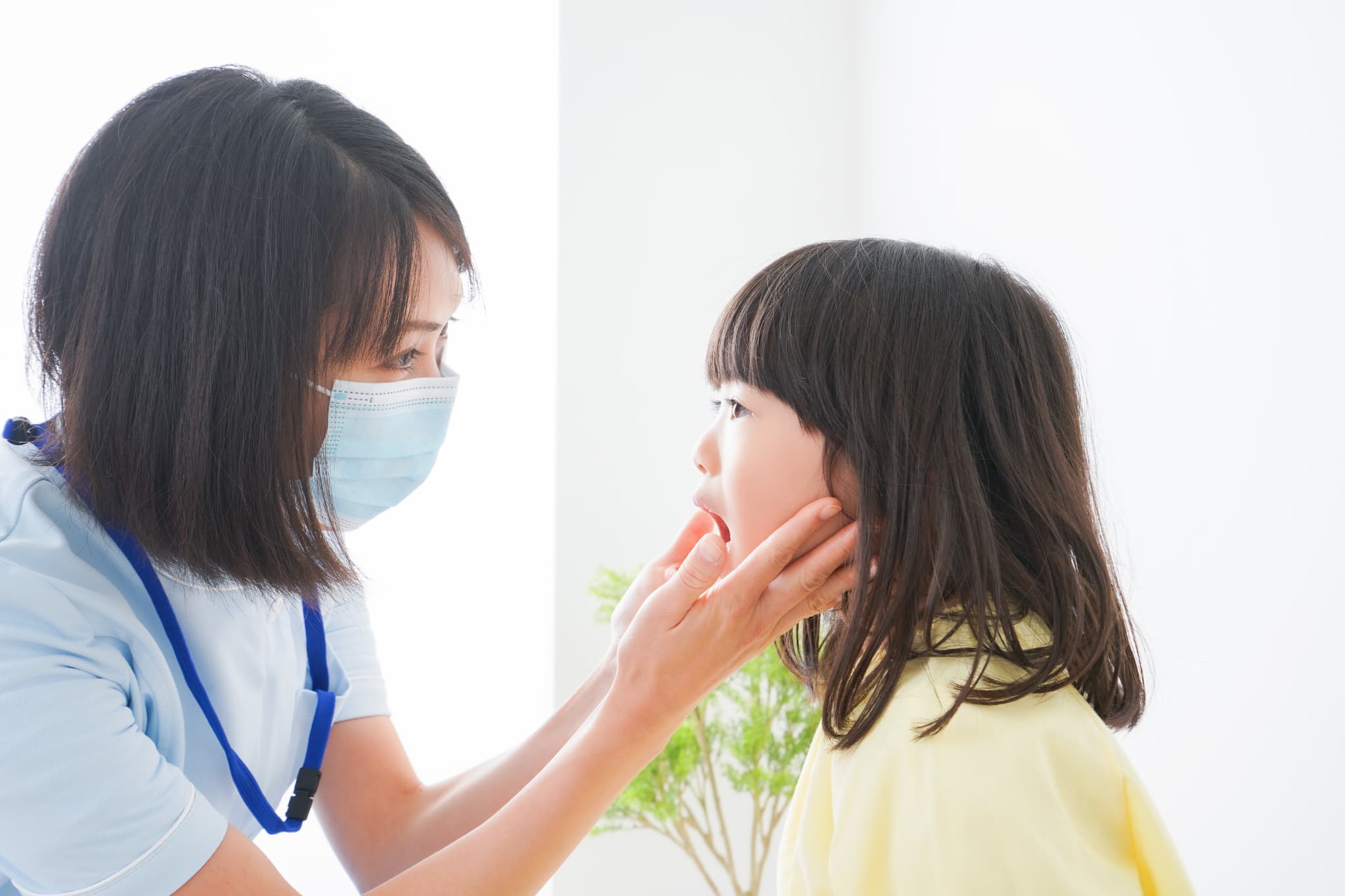 受け口をチェックする歯科衛生士と子ども