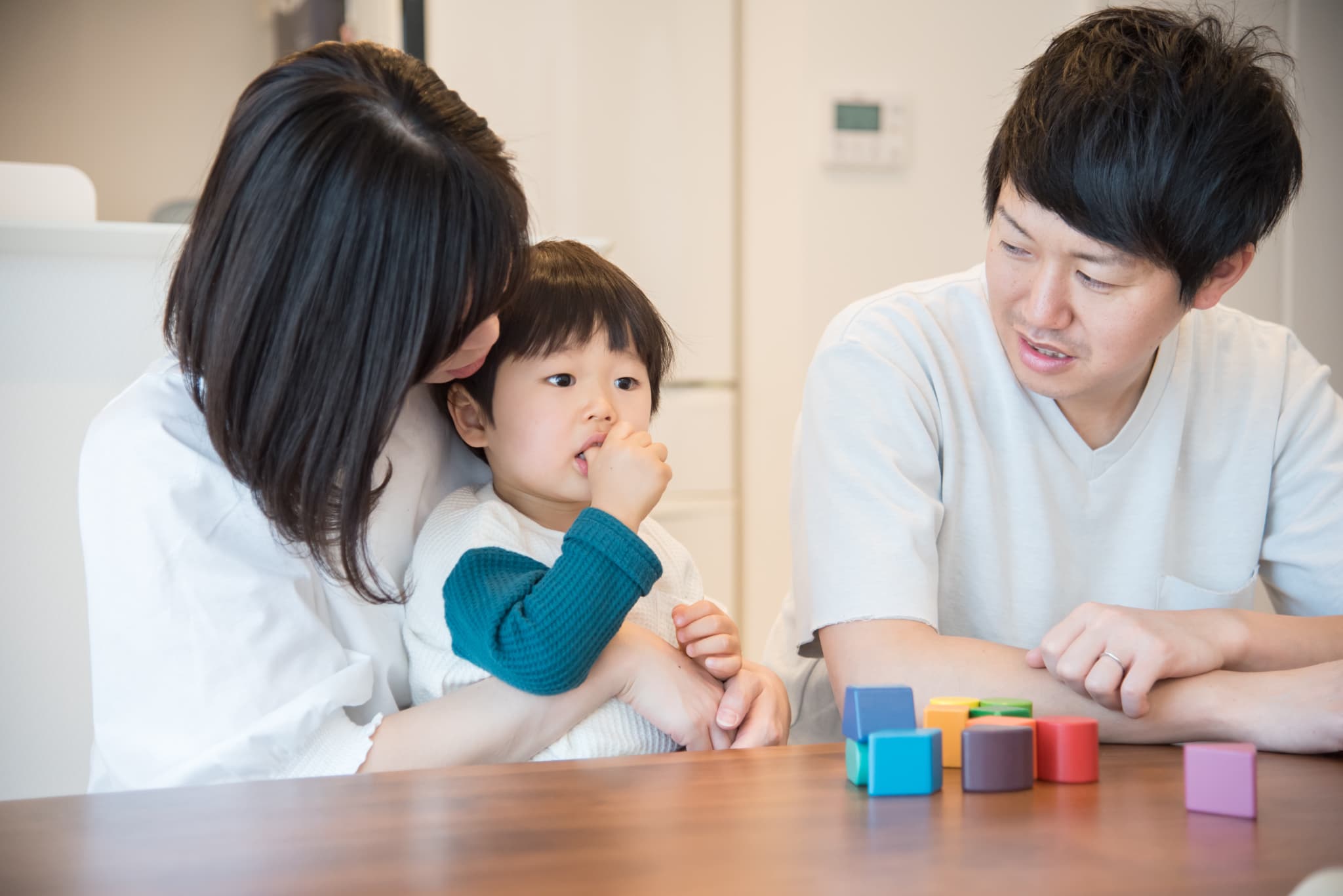 指しゃぶりする子どもと見守る両親