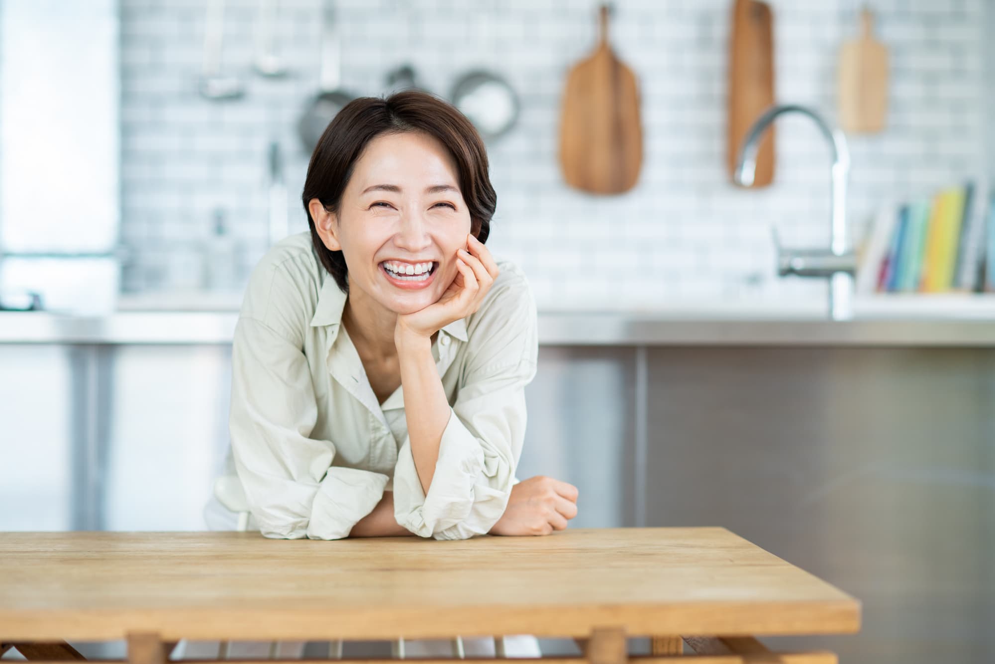 ダイニングで頬杖をつき微笑む女性