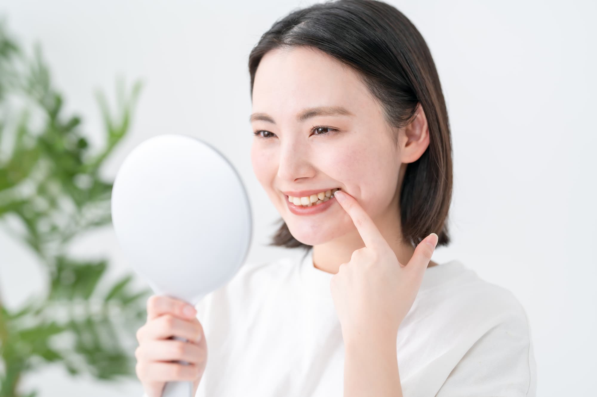 審美歯科で治療した前歯を鏡で見て喜ぶ女性