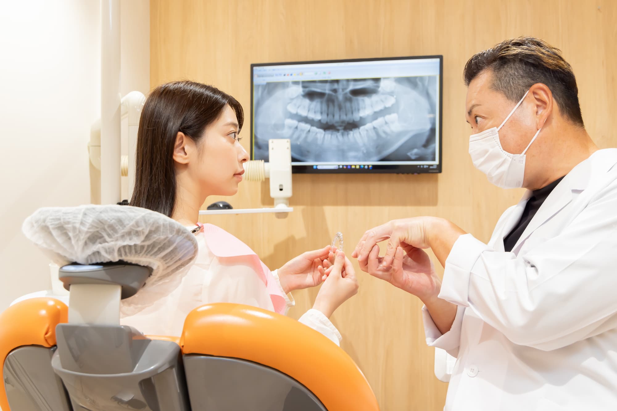 マウスピース矯正の装置が浮いて歯科医に相談する女性